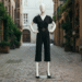 A woman confidently wearing a stylish black capri jumpsuit with elegant accessories in a chic urban setting.