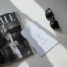 A stylishly arranged flat lay featuring a fashion magazine, a pair of classic sunglasses, and a card with an inspiring fashion quote.