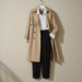 A woman wearing a chic, neutral-toned outfit from a minimalist fashion brand, standing in a simple, well-lit setting.