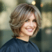 A stylish woman with a modern, medium-length layered haircut, smiling and showing off her new fashion hair.
