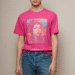 A stylish person wearing a vibrant pink graphic tee with a cool, artistic design, paired with blue jeans and standing against a neutral background.