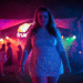 A confident woman wearing a vibrant, holographic plus size rave dress, smiling under festival lights.