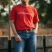 A person wearing a stylish red graphic tee paired with blue jeans, showcasing a confident and casual look.