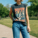 A person wearing a stylish black sleeveless graphic tee with a vintage rock band logo, paired with blue jeans.
