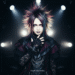 An androgynous person with dramatic spiked hair and elaborate dark clothing, representing the core aesthetic of visual kei fashion.