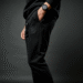 A stylish person wearing a pair of classic black Von Dutch sweatpants with the iconic logo visible on the thigh.