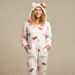 A person wearing a cozy, white and pink hello kitty jumpsuit with a hood that has cat ears and a red bow.
