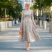 A woman smiling and wearing a stylish long-sleeve floral modest midi dress in a bright, modern setting.
