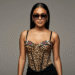 A stylish person wearing a pair of black Ed Hardy shield sunglasses with a visible tiger tattoo graphic on the side.