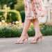 A stylish woman wearing elegant light pink bow heels with a floral summer dress.