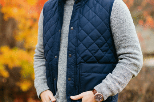 A person wearing a stylish navy blue quilted vest over a gray sweater, standing outdoors on a crisp autumn day.