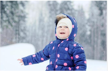 A happy baby wearing a stylish blue Moncler baby down jacket and smiling in a snowy setting.